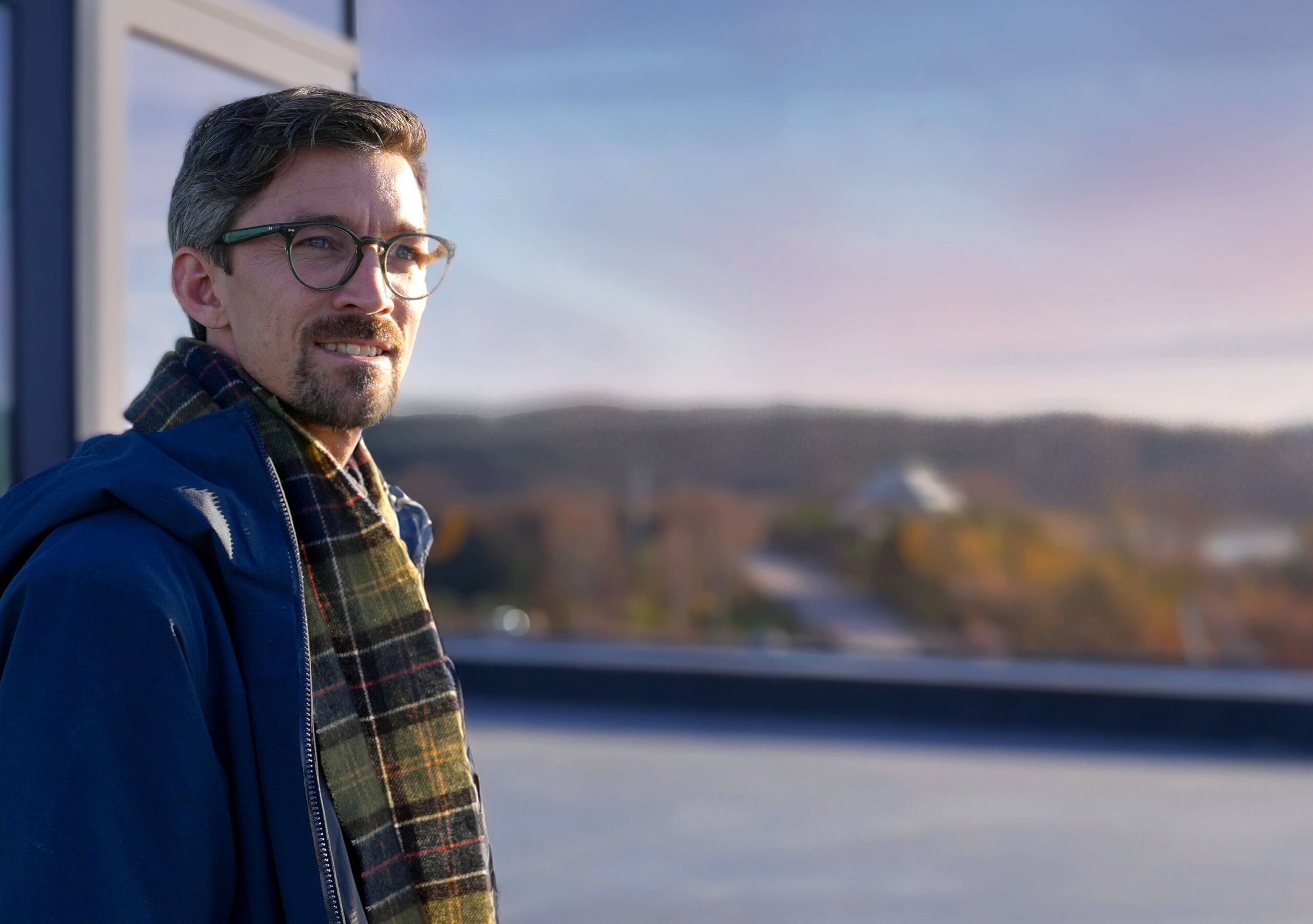 Bild på en man som tittar åt sidan. Mannen står på ett tak.